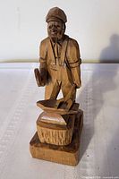 Front view of carved blacksmith figure with anvil on base
