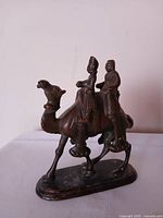 Front view of bronze camel sculpture with two riders