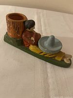 Side view showing full ashtray, match holder, sombrero, and figure