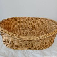 Top view of oval wicker pet bed showing interior weave and lowered front wall