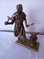 Front view of brass blacksmith figurine showing tools, anvil and base