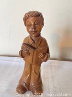 Front view of carved wooden boy holding open book