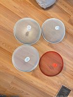 Four round mesh splatter guards laid on floor showing size and color variations