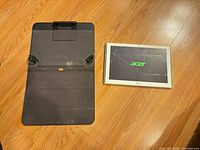 Tablet and folio cover on floor, tablet powered showing Acer logo