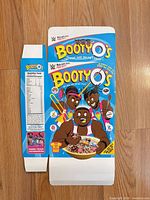 Front of flattened Booty O's cereal box with cartoon wrestler graphics