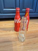 Front view of two Coca-Cola aluminum bottles and Mini Pop glass bottle