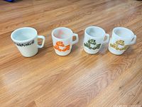 Front view of four Fire-King milk glass mugs showing patterns