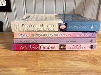 Side view of four paperback books stacked, showing spines with titles and authors