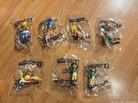 Seven sealed The Simpsons promotional figurines laid out on floor