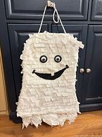 Front view of white ghost pinata with eyes, smile, hanging rope