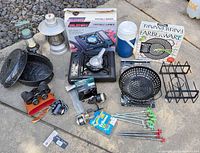 All items arranged on ground showing stove, cookware, lanterns, binoculars, thermos, stakes, accessories