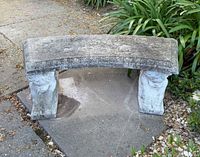 Full view of concrete bench showing curved seat and both cherub supports
