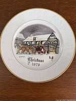Front view of plate showing central Christmas 1979 scene, relief border and gold rim