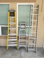 Three ladders standing against wall showing full view