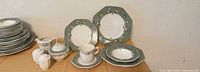 Grouped view of plates, bowls, cup, saucer, sugar bowl, two creamers, salt and pepper shakers