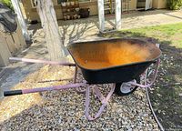 Side view of wheelbarrow showing tub, frame, wheel, flat tire