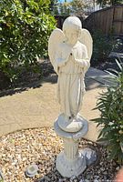 Full view of angel statue on pedestal, garden setting