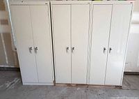 Front view of three beige metal cabinets with closed doors