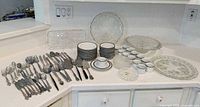 Full lot overview showing porcelain plates, cups, saucers, silver-plate flatware and glass platters