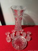 vase, bowl, and several shot glasses arranged on red cloth