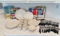 Full lot view showing dinnerware, flatware, and packaged tablecloths