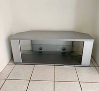 Front view of silver TV stand showing glass shelf and cable ports