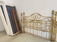 Brass headboard, side rails, mattress and box springs leaning against wall
