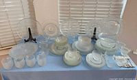 Full lot overview showing variety of clear pressed glass pieces on table