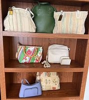 Seven handbags arranged on shelving