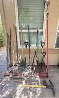 Full view of all long-handled yard tools leaning against wall