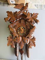 Front view showing full carved wood cuckoo clock with weights and chains