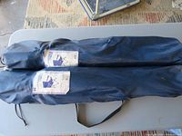 Two folded chairs inside blue carry bags on a table
