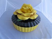 Lidded ceramic trinket dish front view showing yellow rose lid and black fluted rim