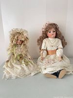 Both dolls seated side by side showing full outfits and scale