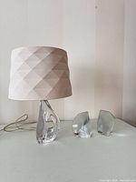 Lamp with shade alongside two clear glass bookends
