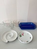 Group view of all items: three measuring cups, two blue casseroles, two plates