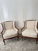 Front view of both armchairs displaying overall design, upholstery, and wood frames