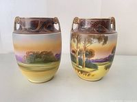 Front view of both Nippon vases showing landscape decoration and handles