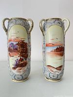 Full front view of both vases showing hand-painted scenes, handles, pattern