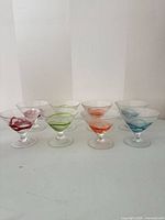 Eight hand-blown martini glasses in two rows showing swirl colors and overall form