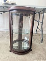 Full front view of cylindrical wood and glass display case showing shelf and panels