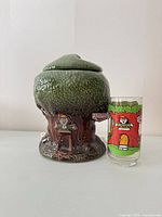Front view of Keebler tree cookie jar beside glass tumbler