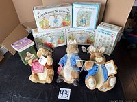 Overall lot showing boxed Wedgwood nursery sets, boxed melamine set, Avon trinket box, three tagged plush rabbits, and shaker box