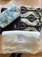 All four throw blankets laid out: blue moon print, black Southwestern pattern, navy bear motif, white knit