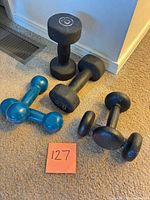 All three pairs of dumbbells on carpet: 4 lb blue vinyl, 5 lb small black cast-iron, 20 lb larger black rubber hex