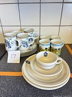 Group shot showing all mugs, cups, saucers, plates and bowl