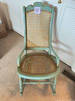 Front view of turquoise rocking chair showing cane seat and back
