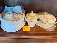 Group view of wrapped teacups, Sango teapot, Limoges covered dish and platter