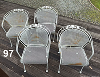 Top view of four matching white wrought iron patio armchairs on deck