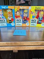 Front view of three sealed character dolls Snap, Pop and Crackle in their original Kellogg’s Rice Krispies boxes